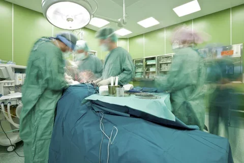 Surgeons in the operating room. The people are blurred to show motion. 