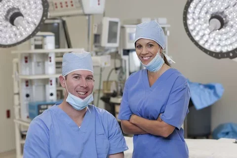 Male and female surgeon in scrubs smiling