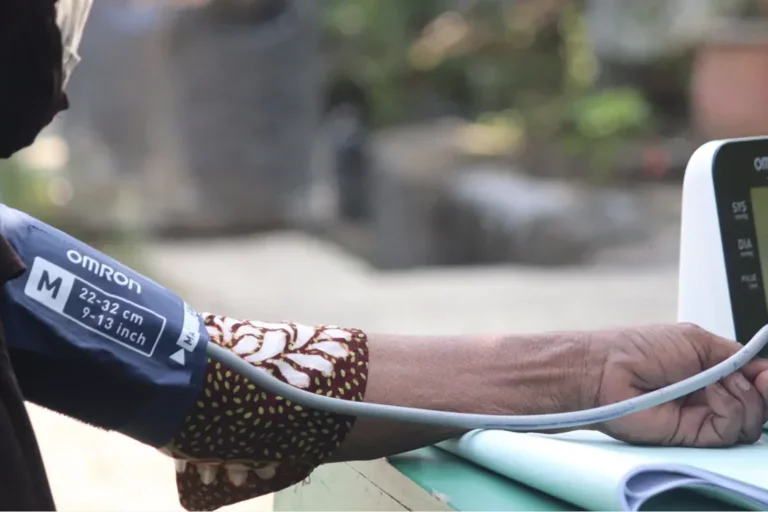 A person holds their arm out to get their blood pressure read using an Omron machine