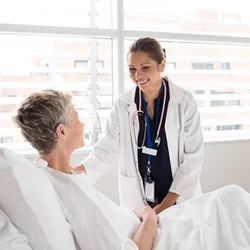 A female doctor smiles at an elderly patient in a hospital bed