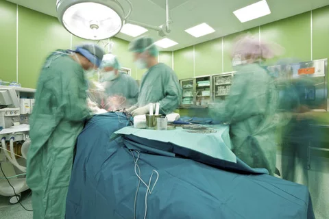 Surgeons in the operating room. The people are blurred to show motion.