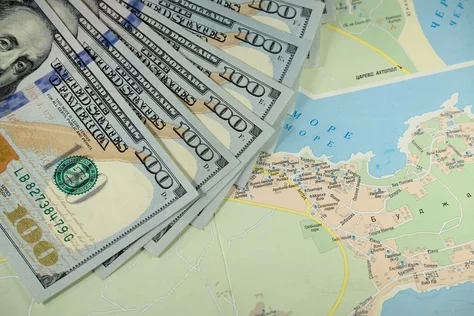 Paper money is spread out on top of a map.